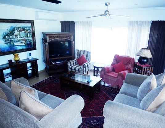 Bright open lounge with sofas, DStv and coastal art in a Shores apartment